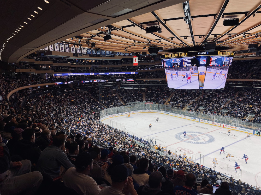 crowds watch the NY Rangers play hockey on the ice at madison square garden in nyc