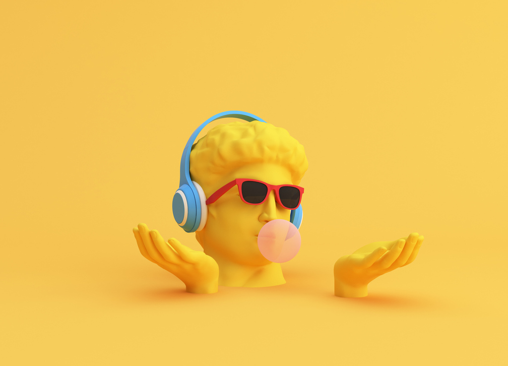 a bright yellow male statue head is seen on a yellow background. the head is wearing blue headphones, red sunglasses, and blowing a bubble of bubble gum.